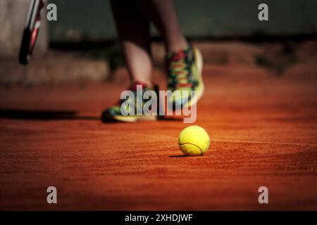 Un tennista si prepara a servire una palla su un campo in terra battuta. Foto Stock