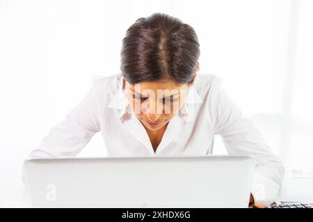 Una donna lavora al tavolo con un portatile e una calcolatrice Foto Stock