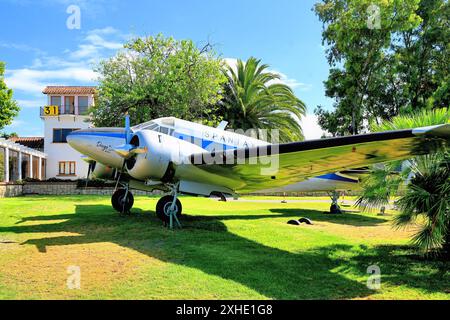 Malaga Aero Museum Aeromuseo e un Beechcraft 18 parcheggiato dalla torre di controllo contro palme e cielo blu sullo sfondo Foto Stock