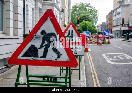 Le indicazioni stradali rosse e triangolari segnalano la presenza di lavori stradali e corsie strette. Foto Stock