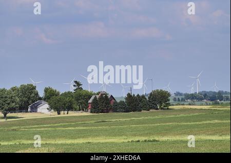 Lee, Illinois, Stati Uniti. Un fienile tradizionale e altre strutture forniscono un primo piano a un gruppo di turbine eoliche in un'area dell'Illinois centro-settentrionale. Foto Stock