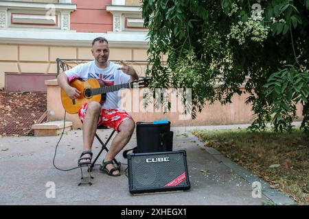 Odessa, Ucraina. 13 luglio 2024. Un musicista di strada suona in Piazza Dumskaya. Dal venerdì sera fino alla fine della domenica, il centro turistico di Odessa fa da sfondo all'esibizione di molti musicisti di strada. Alcuni giocano vicino a ristoranti, altri - in luoghi turistici della città. Con l'inizio del buio, il rumore proveniente dai generatori a causa di interruzioni di corrente dovute a una carenza di elettricità aumenta la varietà di suoni sulle strade della città. Credito: SOPA Images Limited/Alamy Live News Foto Stock