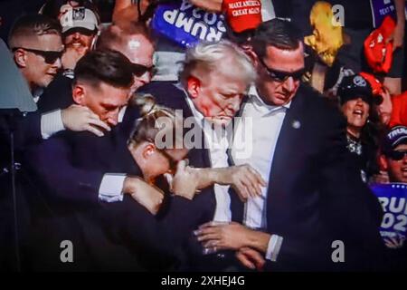 In questa illustrazione fotografica, uno schermo mostra l'ex presidente degli Stati Uniti Donald Trump girato all'orecchio durante una manifestazione che stava tenendo a Butler. L'ex presidente degli Stati Uniti Donald Trump è stato ferito in una sparatoria a un raduno che stava tenendo a Butler, Pennsylvania, nell'ambito della sua campagna elettorale in vista delle elezioni presidenziali statunitensi del 2024. Secondo gli ultimi rapporti, agenti segreti hanno ucciso un assassino e un partecipante al rally è morto per mano dello stesso assassino, la sparatoria al rally è stata indagata come un tentato omicidio dell'ex presidente Trump, la Associated Press riferisce che citava il Butler Foto Stock