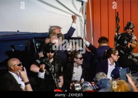 In questa illustrazione fotografica, uno schermo mostra l'ex presidente degli Stati Uniti Donald Trump girato all'orecchio durante una manifestazione che stava tenendo a Butler. L'ex presidente degli Stati Uniti Donald Trump è stato ferito in una sparatoria a un raduno che stava tenendo a Butler, Pennsylvania, nell'ambito della sua campagna elettorale in vista delle elezioni presidenziali statunitensi del 2024. Secondo gli ultimi rapporti, agenti segreti hanno ucciso un assassino e un partecipante al rally è morto per mano dello stesso assassino, la sparatoria al rally è stata indagata come un tentato omicidio dell'ex presidente Trump, la Associated Press riferisce che citava il Butler Foto Stock