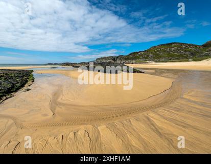 Graziosi motivi a forma di rivuleto nella sabbia gialla della spiaggia di Kiloran con cielo blu sopra sulla remota isola Ebridea di Colonsay, Scozia, Regno Unito Foto Stock