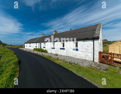 Grazioso "Crumble Cottage", cottage per le vacanze appena imbiancato con strada asfaltata nera appena ripavimentata, Uragaig, Isola di Colonsay, Scozia, Regno Unito. Foto Stock