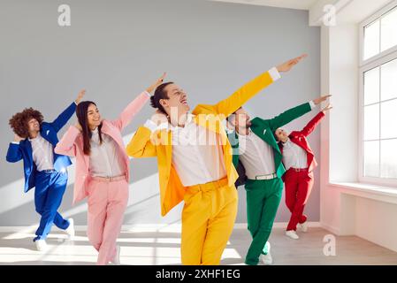 Persone d'affari colorate in abiti brillanti, danze dinamiche ed emotive. I movimenti danzanti sincronizzati dipingono vivaci immagini ritmi gioiosi di balli Foto Stock