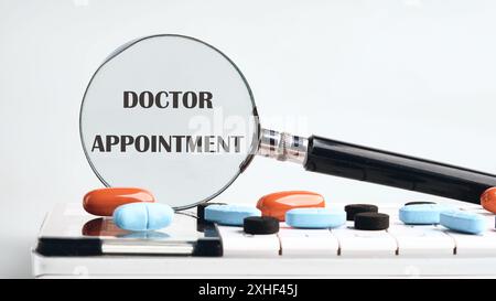 Le parole APPUNTAMENTO MEDICO scritte attraverso una lente d'ingrandimento su una calcolatrice con compresse su sfondo grigio. Il concetto di medicina Foto Stock