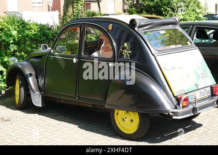 Lingen, Germania - 13 maggio 2024 Un Citroën deux cheveaux nero parcheggiato con parti gialle. Una rara vista di questo famigerato oldtimer Foto Stock