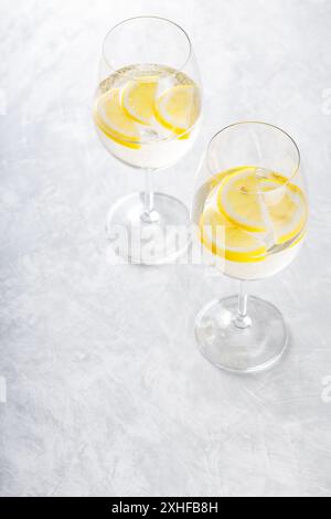 Cocktail Hugo Spritz in vetro con Limone su sfondo grigio, bevanda alcolica estiva Foto Stock