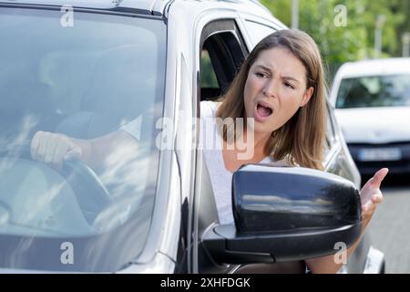 la ragazza infelice sta gesticolando attivamente al volante Foto Stock