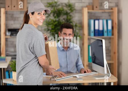 corriere che consegna il pranzo fresco a un uomo d'affari in ufficio Foto Stock