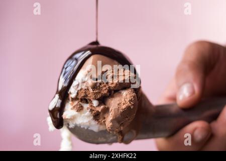 Un bicchierino di cioccolato e gelato alla vaniglia con sciroppo di cioccolato da versare sopra, con sfondo sfocato Foto Stock