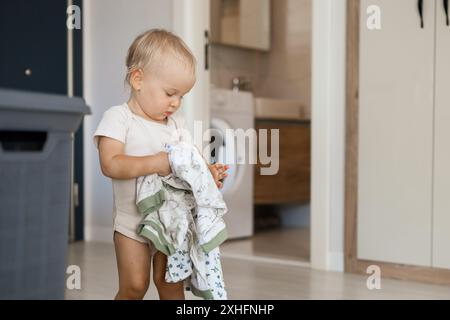 la piccola figlia caucasica aiuta la madre con un bucato Foto Stock