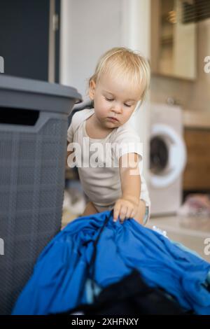 la piccola figlia caucasica aiuta la madre con un bucato Foto Stock