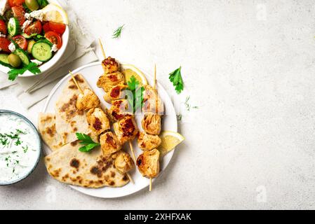 Pranzo salutare mediterraneo: Spiedini di pollo souvlaki, focaccia e insalata di verdure. Kebab di pollo fritto, insalata greca, salsa di yogurt tzatziki e pi Foto Stock