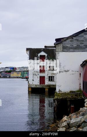 Uno scatto verticale degli edifici abbandonati lungo la riva di Goma nel porto di Kristiansund, Norvegia, in una giornata nuvolosa Foto Stock