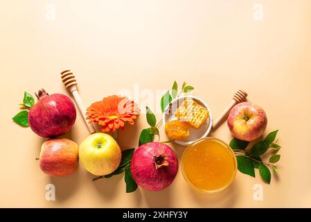 Rosh Hashanah, allestimento creativo per le vacanze del capodanno ebraico. Modello di biglietto d'auguri con simboli tradizionali: Mele, miele, melograno e fiori sul beige Foto Stock