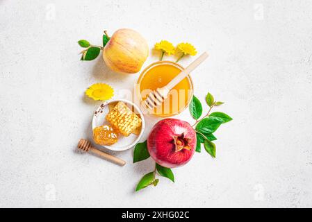 Composizione creativa di Rosh Hashanah. Melograno, mele e miele simbos tradizionali per festeggiare su sfondo bianco in cemento, vista dall'alto. Au. Ebreo Foto Stock