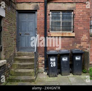 Tre cassonetti neri con il logo del Derbyshire Dales District Council, in fila sul retro di 27 St Johns Street, Wirksworth, Derbyshire Foto Stock