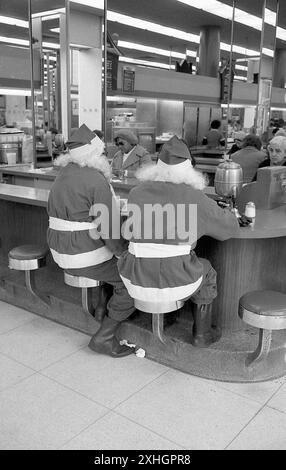 New York, NY, 1976: In una gastronomia a Manhattan, un paio di clausole di Babbo Natale dell'Esercito della salvezza si prendono una pausa dal stare in piedi lungo i marciapiedi chiedendo agli acquirenti di donazioni. Foto Stock