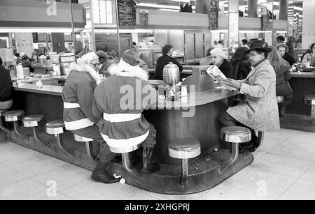 New York, NY, 1976: In una gastronomia a Manhattan, un paio di clausole di Babbo Natale dell'Esercito della salvezza si prendono una pausa dal stare in piedi lungo i marciapiedi chiedendo agli acquirenti di donazioni. Foto Stock