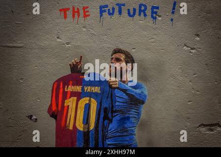 Barcellona, Spagna. 14 giugno 2024. Un pendolare passa davanti a un murale dell'artista urbano italiano "TVBoy", Salvatore Benintende. Intitolato "il futuro", i graffiti raffigurano Lionel messi in possesso di una maglia del FC Barcelona con il suo ex numero 10 e il nome Lamine Yamal, presentando la giovane stella il giorno in cui potrebbe diventare il più giovane vincitore di un campionato europeo di UEFA, come suo successore. Crediti: Matthias Oesterle/Alamy Live News Foto Stock