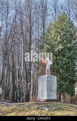 Mosca, Russia - 5 aprile 2024: Scultura di un ragazzino in cravatta rossa con il bugle pioniere sul piedistallo. Monumento standard dell'epoca sovietica nel vecchio parco. Primavera la Foto Stock