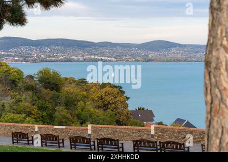 Una nave a vela sul lago Balaton alla luce del sole autunnale con Balatonfüred sullo sfondo Foto Stock