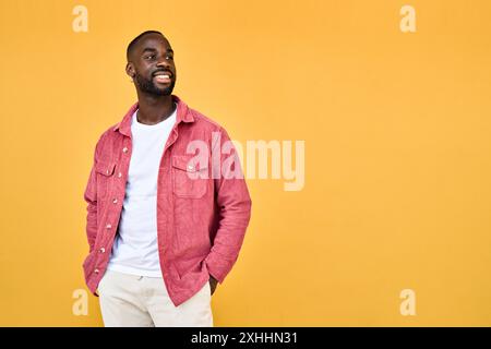 Giovane uomo afroamericano felice in piedi isolato con lo sguardo giallo lontano. Foto Stock
