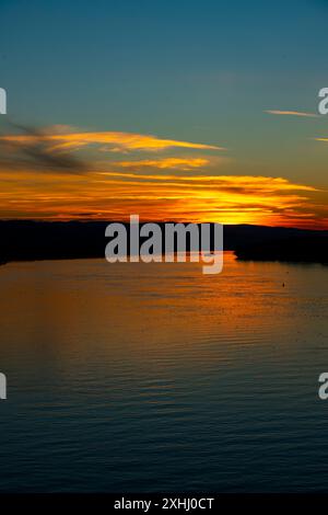 Lo splendido tramonto illumina il fiume Danubio a Novi Sad, Serbia, con vivaci sfumature di arancione e blu, che si riflettono pacificamente sulle acque calme Foto Stock