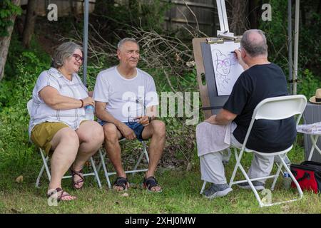 Una coppia di anziani ama un artista caricaturale che disegna il proprio ritratto all'aperto in un parco Foto Stock