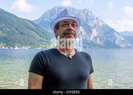 Ritratto di un uomo barbuto anziano di 50-55 anni in un cappello bianco sorridente vicino a un lago in Austria Foto Stock