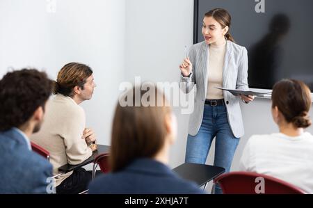 Ritratto di una giovane donna d'affari che si trova vicino al consiglio interattivo e partecipa a un seminario aziendale in auditorium Foto Stock