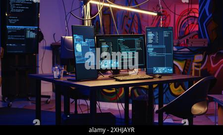 Jib down di un sistema informatico a tecnologia avanzata che esegue codice dannoso in un magazzino vuoto. I monitor per PC in graffiti vuoti dipingono un nascondiglio sotterraneo utilizzato dagli hacker per commettere attività illecite Foto Stock