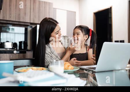 Mamma e figlia si godono momenti di qualità mentre lavorano da casa in un ambiente moderno Foto Stock