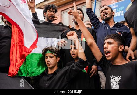 Srinagar, India. 14 luglio 2024. I musulmani sciiti del Kashmir gridano slogan filo-palestinesi mentre detengono una bandiera palestinese durante una processione di Muharram il settimo giorno di Muharram. Muharram è il primo mese del calendario islamico. È uno dei mesi più sacri del calendario islamico. I musulmani sciiti commemorano Muharram come un mese di lutto in ricordo del martirio del profeta islamico Imam Hussain, nipote del profeta islamico, che fu martirizzato su Ashura (10° giorno di Muharram) nella battaglia di Karbala nel 680 d.C. credito: SOPA Images Limited/Alamy Live News Foto Stock