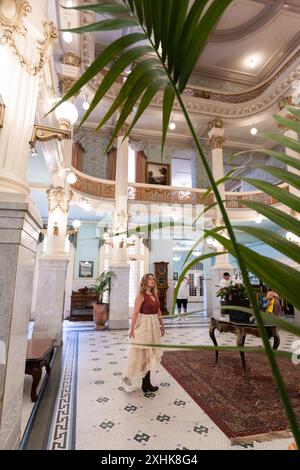 Le donne ospiti camminano intorno all'atrio della hall dorata dove persone famose socializzavano in passato, lo storico Menger Hotel, San Antonio, Texas, USA Foto Stock