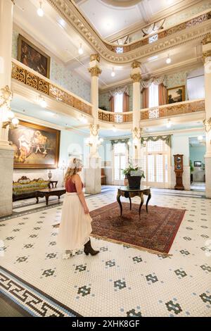 Le donne ospiti camminano intorno all'atrio della hall dorata dove persone famose socializzavano in passato, lo storico Menger Hotel, San Antonio, Texas, USA Foto Stock