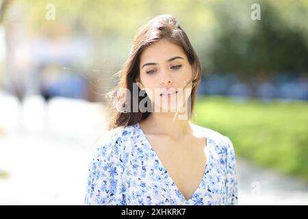 Vista frontale ritratto di una donna distratta che cammina per strada Foto Stock