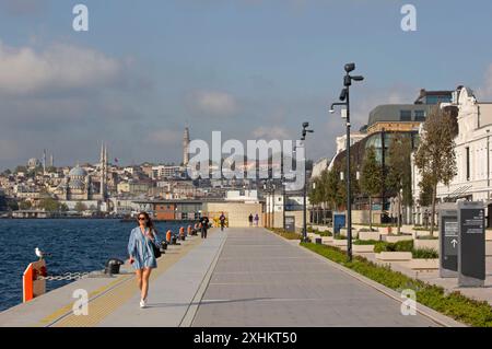 Turchia, Istanbul, Galataport, giovane donna in abito che passeggia sulla passeggiata marittima di Galataport, di fronte alle moschee di Sultanahmet Foto Stock