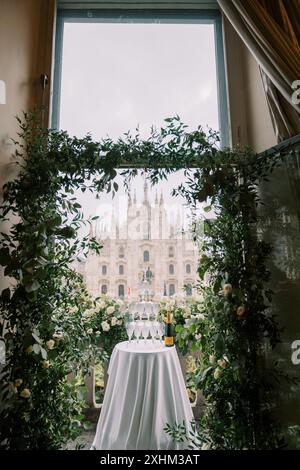 Un mucchio di bicchieri si erge su un tavolo accanto a una bottiglia di champagne su un balcone che si affaccia sul Duomo. Milano, Italia Foto Stock