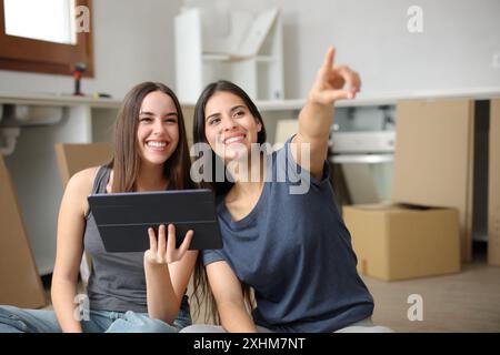 Due coinquilini felici che stanno progettando una riforma in cucina mentre si trasferivano casa Foto Stock