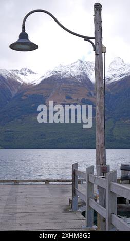 Una vista panoramica di un molo con una lampada d'epoca e montagne innevate in nuova Zelanda Foto Stock