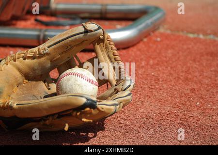 Un vecchio guanto da baseball e il baseball giacciono sul prato Foto Stock