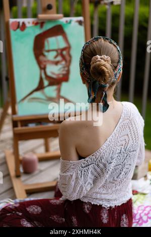 Una donna artista dipinge un quadro su un cavalletto. Foto Stock