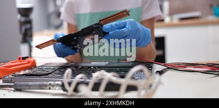 Primo piano delle correzioni tecniche della scheda madre del notebook nel centro di assistenza. Computer portatile che disassembla parti e dispositivi Foto Stock