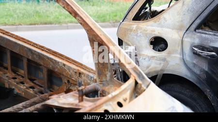 Primo piano di parti in ferro del veicolo bruciato, auto dopo incidente. Sommosse, proteste civili, teppisti o criminali in concetto di città Foto Stock