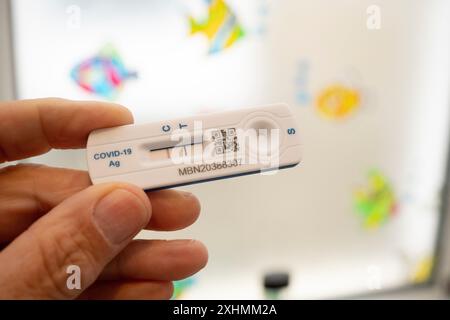 Un dettaglio di una mano che tiene una prova di flusso laterale di Covid che mostra un risultato positivo in un bagno, 13 luglio 2024, a Londra, Inghilterra. Foto Stock