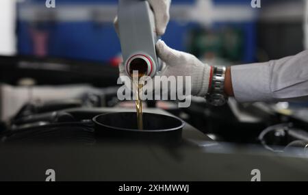 Rifornimento e versamento dell'olio del meccanico automatico nel motore della vettura Foto Stock